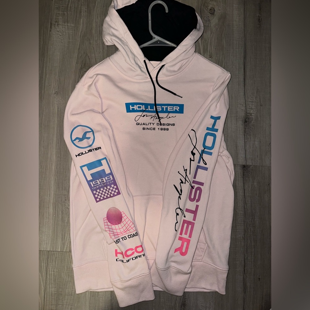 Hollister men’s pink pullover hoodie with company decals on sleeves